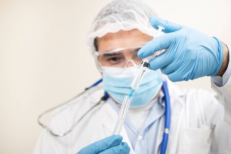 View of caucasian doctor with  syringe and test tube on a white background.