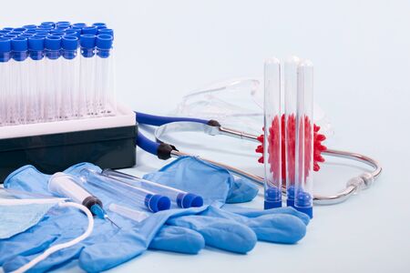 Several laboratory objects including protective mask, gloves, vial rack, testing tubes and other...