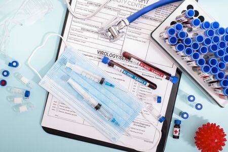 Several fictional infected blood samples with various virus with a lab report, mask and syringe.