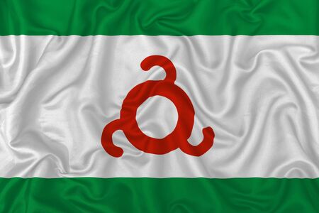 Republic of Ingushetia flag on wavy silk textile fabric background.の写真素材