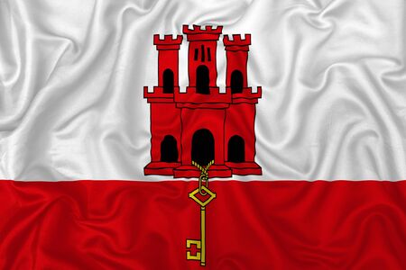 Gibraltar flag on wavy silk textile fabric background.の写真素材