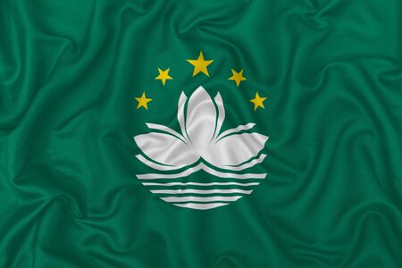 Macau city flag on wavy silk textile fabric background.の写真素材