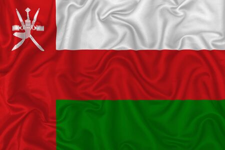 Oman country flag on wavy silk textile fabric background.の写真素材