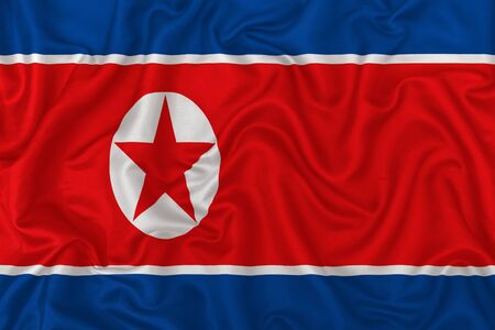 North Korea country flag on wavy silk textile fabric background.