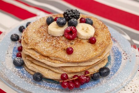Delicious oats and banana pancakes with mixed berries fruits and sugar powder.の写真素材