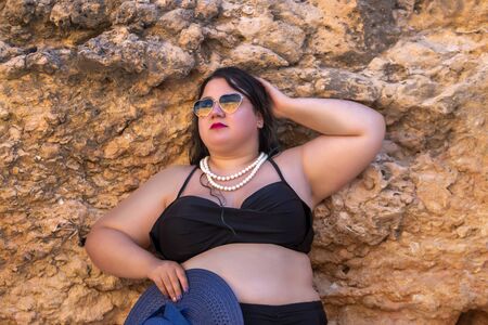 beautiful sensual woman with black bikini and dark shades on the beach.