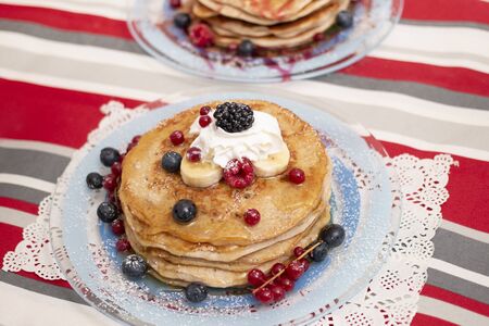 Delicious oats and banana pancakes with mixed berries fruits and sugar powder dripping with honey.