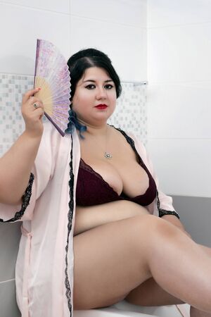 woman in sensual pink bathrobe and lingerie on the bathtub.の写真素材