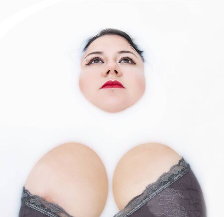 woman wearing sensual lingerie on a milky bathtub.の写真素材
