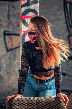 Dangerous girl with pink mouth mask on a abandoned factory using an old sofa.の写真素材