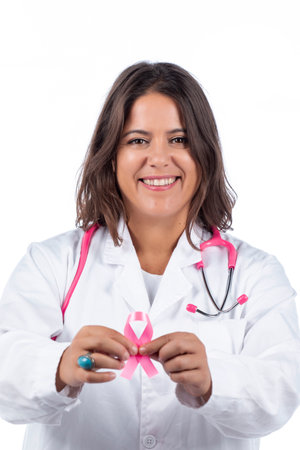 Caucasian doctor woman with pink stethoscope holding breast cancer pink ribbon on a white background.の写真素材