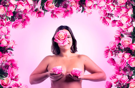 Sensual girl holding roses covering breasts, over a white background.の写真素材
