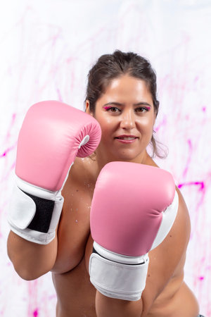 girl with pink boxing gloves fighting breast cancer over a splatter dripping background.