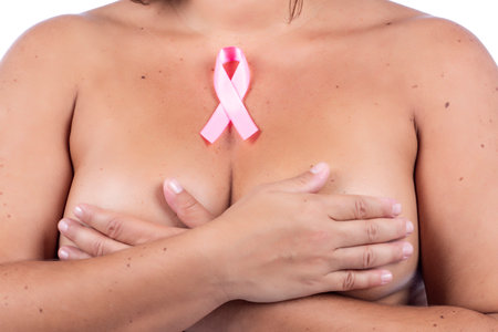 Nude caucasian girl with breast cancer ribbon over a white background.の写真素材