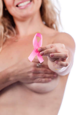 Adult woman covering breasts with hands holding breast cancer awareness pink ribbon, over a white background.の写真素材