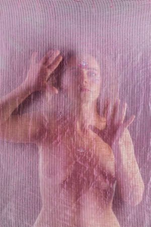 Caucasian woman with transparent fabric on a black background.の写真素材