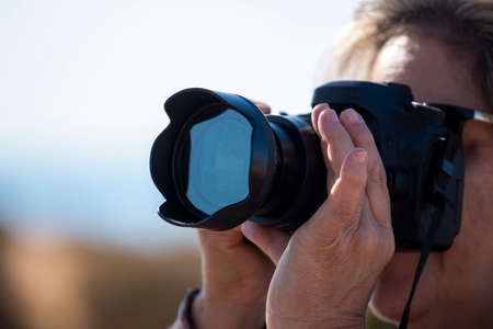 Close up view of a Photographer using a dslr camera in an outdoor setting.