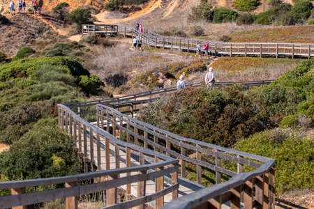 LAGOS, PORTUGAL - OCTOBER 23, 2021: Tourists walking by wooden boardwalk near the coastline cliffs of Lagos, Portugal.のeditorial素材