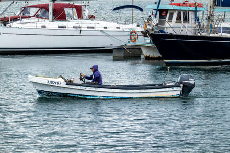 OLHAO, PORTUGAL - 13th FEBRUARY 2022: Fisherman on small fishing boat cruising around the docks.