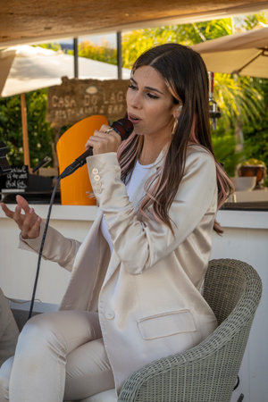 QUINTA DO LAGO, PORTUGAL - 26th JUNE 2022: Band duo singer and guitar player called Beatriz playing in a beach bar restaurant in Quinta do Lago.のeditorial素材