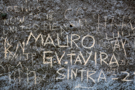 Close up view of several carved names on an old weathered cement wall.