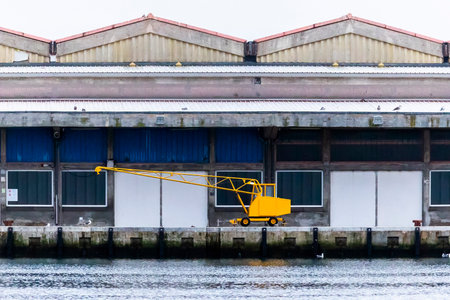 Close up view of a small yellow crane for unloading fisherman ships on the docks to the warehouses.