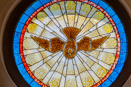Stained glass window with some kind of bird or dove depicted inside a Christian church in Portugal.