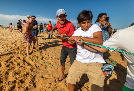 QUARTEIRA, PORTUGAL - 6th JUNE 2023: Cast net fishing tradition done by the local population at beach seashore.のeditorial素材