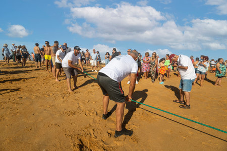 QUARTEIRA, PORTUGAL - 6th JUNE 2023: Cast net fishing tradition done by the local population at beach seashore.のeditorial素材