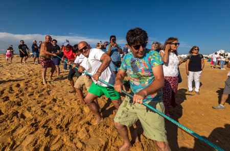 QUARTEIRA, PORTUGAL - 6th JUNE 2023: Cast net fishing tradition done by the local population at beach seashore.のeditorial素材