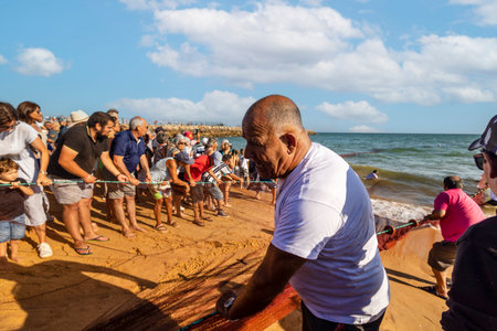 QUARTEIRA, PORTUGAL - 6th JUNE 2023: Cast net fishing tradition done by the local population at beach seashore.のeditorial素材