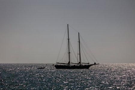 Silhouette of sail boat with shiny water.