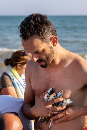 QUARTEIRA, PORTUGAL - 6th JUNE 2023: Cast net fishing tradition done by the local population at beach seashore.のeditorial素材