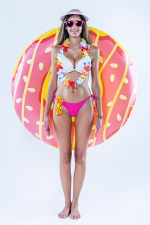 Woman in bikini with large inflatable swimming ring over a gray background.の写真素材