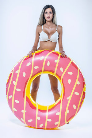 Woman in bikini with large inflatable swimming ring over a gray background.の写真素材