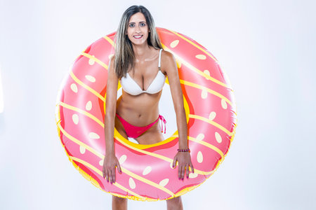 Woman in bikini with large inflatable swimming ring over a gray background.の写真素材
