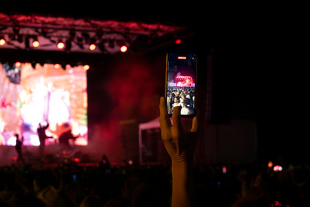 LOULE, PORTUGAL: 26th AUGUST 2023 - An event called White Night, where everybody dresses white clothing and watches shows, concerts and performances, fans using smartphone to record a concert.のeditorial素材