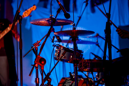 Drum set instrument bathed with blue light on a concert stage.