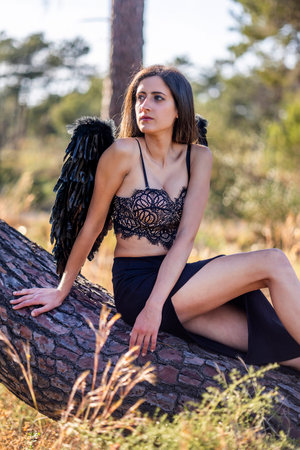 Close view of a beautiful woman in the forest posing with dark wings, that looks like a dark angel.の写真素材