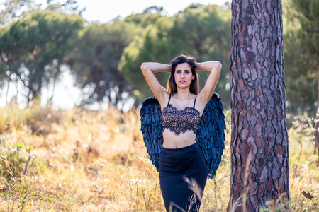 Close view of a beautiful woman in the forest posing with dark wings, that looks like a dark angel.の写真素材