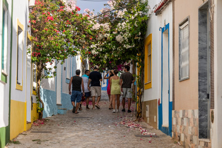 Young people walk in typical street of Ferragudo, located in the Algarve, Portugal.の写真素材