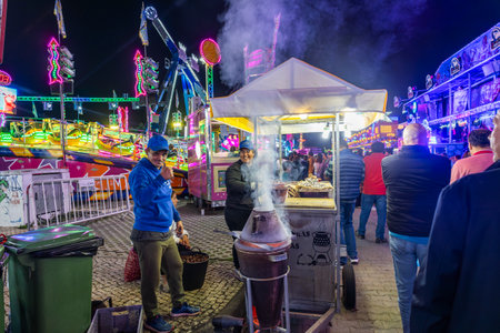 FARO, PORTUGAL - 20th OCOTOBER 2024: Fun fair couple making roasted chestnuts, part of the Magusto tradition, with charcoal announcing the arrival of the autumnの写真素材