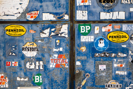 SAO BRAS DE ALPORTEL, PORTUGAL: 4th MAY, 2024 - Rust metal door with several advertisement stickers worn by time and weathering.のeditorial素材