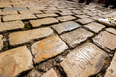 LOULE, PORTUGAL - 17th MARCH 2024: Several names, symbols and words on a cobblestone street near the tavern "O Postigo".のeditorial素材