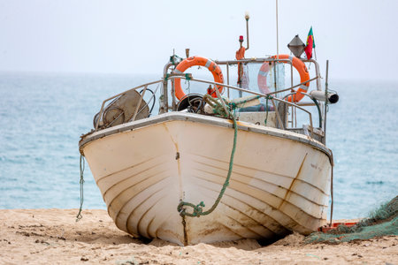 Traditional Portuguese fishing boat anchored on the beach in the Algarve region.の写真素材
