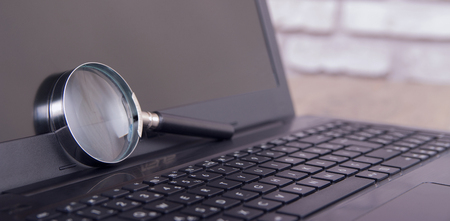 magnifying glass on black laptopの写真素材