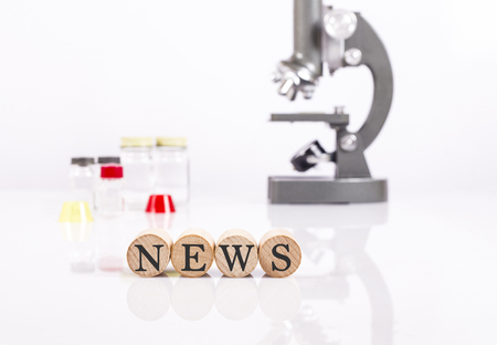 writing news front of microscope and test tubes for health and science newsの写真素材