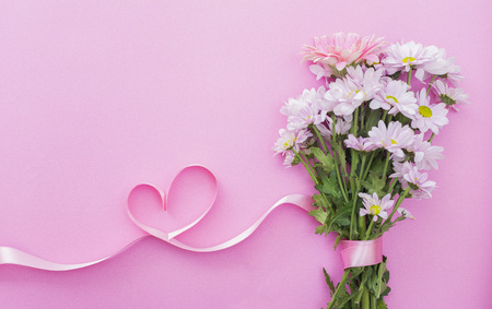 daisy bouquet and heart shaped ribbon, on pink backgroundの写真素材