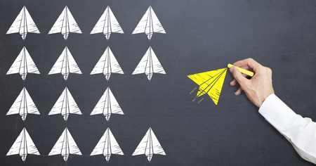man is drawing yellow paper plane icon on blackboard. leadership concept