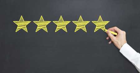 man drawing five stars on blackboard for customer rating.の写真素材